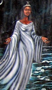 Image of a brown-skinned feminine figure in a flowing white dress standing in water, with a dark background. 